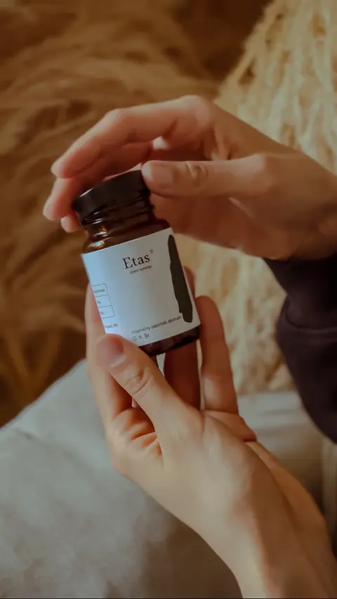Dłonie otwierające słoiczek suplementu Kogen Etas – zdjęcie produktowe