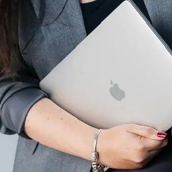 Kobieta trzymająca laptopa MacBook – opieka techniczna nad stroną, digital grow
